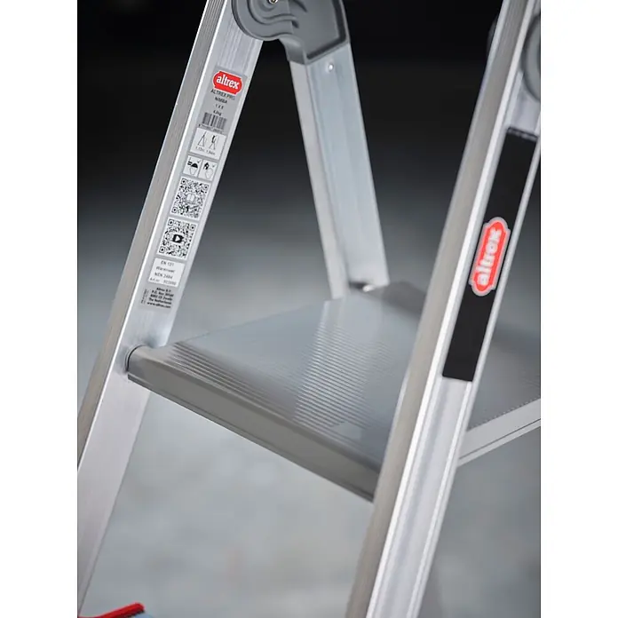 Altrex Stehleiter Nimba Stufenstehleiter einseitig begehbar 5 Stufen - Anzahl Tritte: 5 Stk., Arbeitshöhe: 3.100 m, Aluminium - Eine silberne Altrex-Aluminium-Stehleiter mit einer grauen, geriffelten Stufe und einem Produktetikett mit Sicherheitshinweisen.