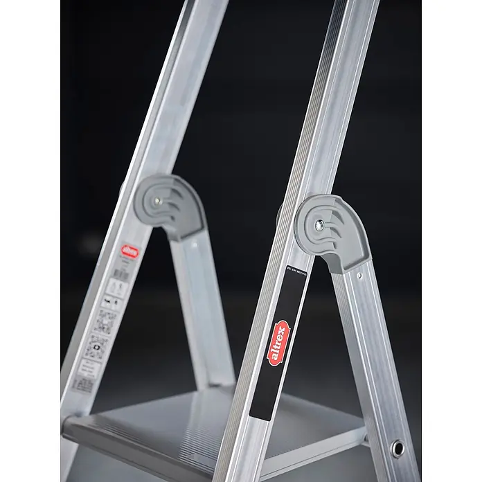 Altrex Stehleiter Nimba Stufenstehleiter einseitig begehbar 5 Stufen - Anzahl Tritte: 5 Stk., Arbeitshöhe: 3.100 m, Aluminium - Nahaufnahme einer silbernen Aluminium-Klappleiter mit grauen Stufen und Gelenken, mit rotem 'altrex' Logo.