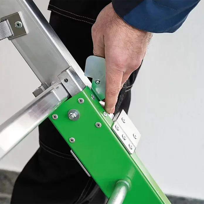 Munk Podestleiter Einsteckteil Plus 4 Stufen für steckbare Plattformleiter - Aluminium - Hand drückt hellgrünen Sicherheitsverschluss an grünem und silbernem Mehrzweckleiter-Mechanismus.