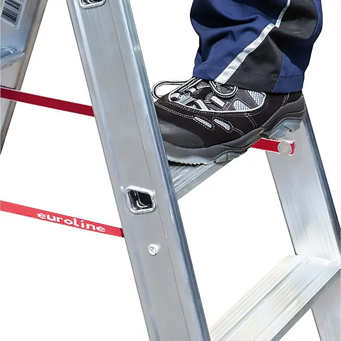 Euroline Stehleiter Premium 30577 Stufenstehleiter 2x16 Stufen - Anzahl Tritte: 16 Stk., Arbeitshöhe: 5.300 m, Belastbarkeit: 150 kg, Aluminium - Aluminiumleiter mit einem Sicherheitsschuh auf einer Sprosse und rotem 'euroline'-Gurtband.