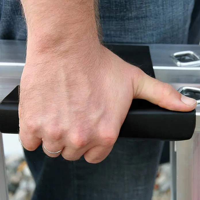 Munk Stehleiter Stehleiter mit clip-step 5 Stufen - Anzahl Tritte: 5 Stk., Arbeitshöhe: 3.150 m, Aluminium - Hand greift einen schwarzen gepolsterten Griff eines silbernen Metallprodukts.