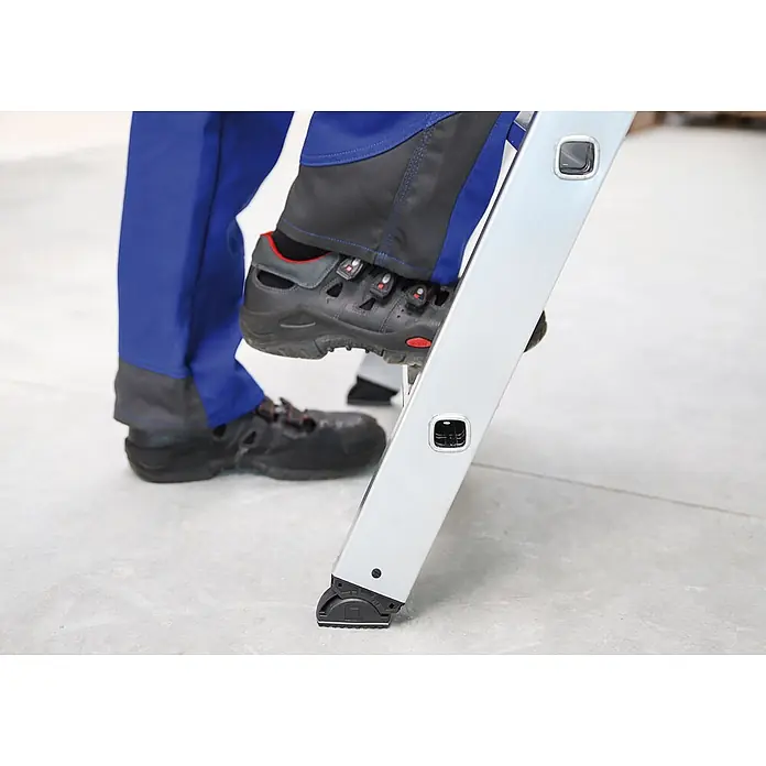 Munk Stehleiter Stehleiter mit clip-step 5 Stufen - Anzahl Tritte: 5 Stk., Arbeitshöhe: 3.150 m, Aluminium - Fuß in Sicherheitsschuh auf silberner Leiterstufe. Rutschfester Leiterfuß am Boden für Stabilität.