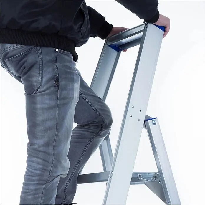 ASC Stehleiter Eurostairs Stufenstehleiter einseitig eloxiert mit Plattform 4 Stufen - Anzahl Tritte: 4 Stk., Arbeitshöhe: 2.800 m, Aluminium - Person steigt auf eine silberne Aluminium-Stehleiter mit blauen Akzenten.