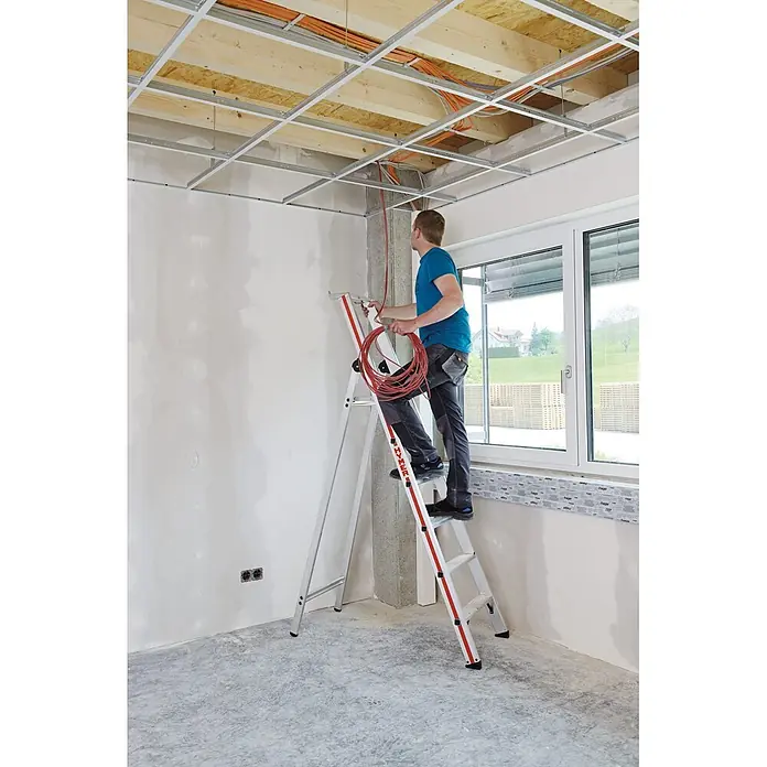 Hymer Stehleiter Stufenstehleiter mit Plattform und Aluminium Ablageschale 7 Stufen - Anzahl Tritte: 7 Stk., Arbeitshöhe: 3.630 m, Aluminium - Silberne Aluminiumleiter mit roten Akzenten, die einen Arbeiter beim Verlegen von Deckenkabeln unterstützt.