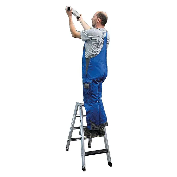 Munk Stehleiter Stehleiter beidseitig begehbar mit clip-step R13 250kg 4 Stufen - Anzahl Tritte: 4 Stk., Arbeitshöhe: 2.450 m, Aluminium - Mann in blauer Arbeitskleidung steht auf silberner Trittleiter und hält Aluminiumprofil zur Montage hoch.