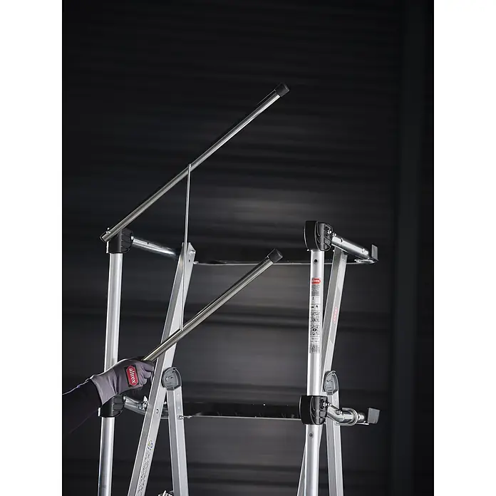 Altrex Podestleiter RolShield Plattformleiter 3 Stufen - Anzahl Tritte: 3 Stk., Arbeitshöhe: 2.700 m - Hand im Altrex-Handschuh justiert silbernes Aluminium-Sicherheitsgeländer an modularem Leitersystem.
