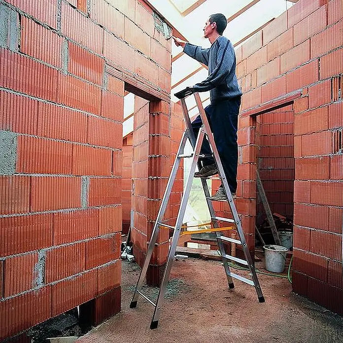Zarges Stehleiter Nova S gebördelte Stehleiter 8 Stufen - Anzahl Tritte: 8 Stk., Arbeitshöhe: 3.700 m, Aluminium - Aluminium-Stehleiter mit gelbem Balken, von einem Mann bei Arbeiten an einer Ziegelwand im Bau verwendet.