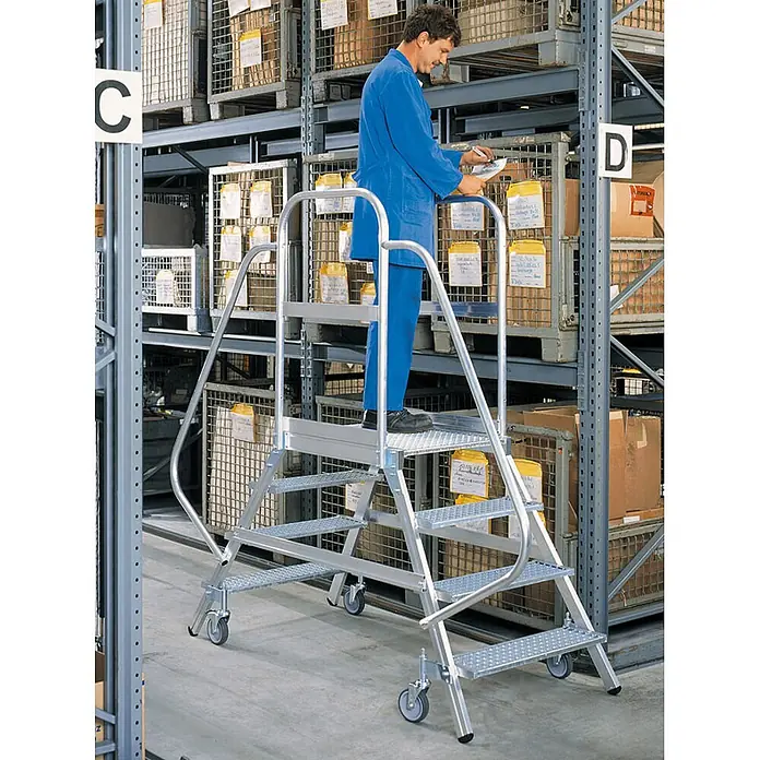 Munk Treppenpodest Podestleiter fahrbar Aluminium geriffelt 2x5 Stufen - Anzahl Tritte: 5 Stk., Arbeitshöhe: 3.200 m, Aluminium - Mobile Arbeitsplattform aus silbernem Aluminium mit Rollen, von einem Arbeiter zum Zugriff auf hohe Lagerregale genutzt.