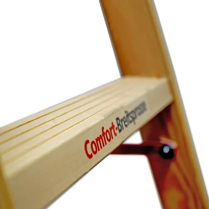 Euroline Stehleiter Holz Sprossenstehleiter mit Comfort-Breitsprossen, Eimerhaken und Werkzeuga - Anzahl Tritte: 5 Stk., Arbeitshöhe: 2.600 m, Holz - Nahaufnahme einer hellen Holzleiterstufe mit Aufschrift 'Comfort-Breitsprosse', Holzmaserung und rotem Metallbeschlag.