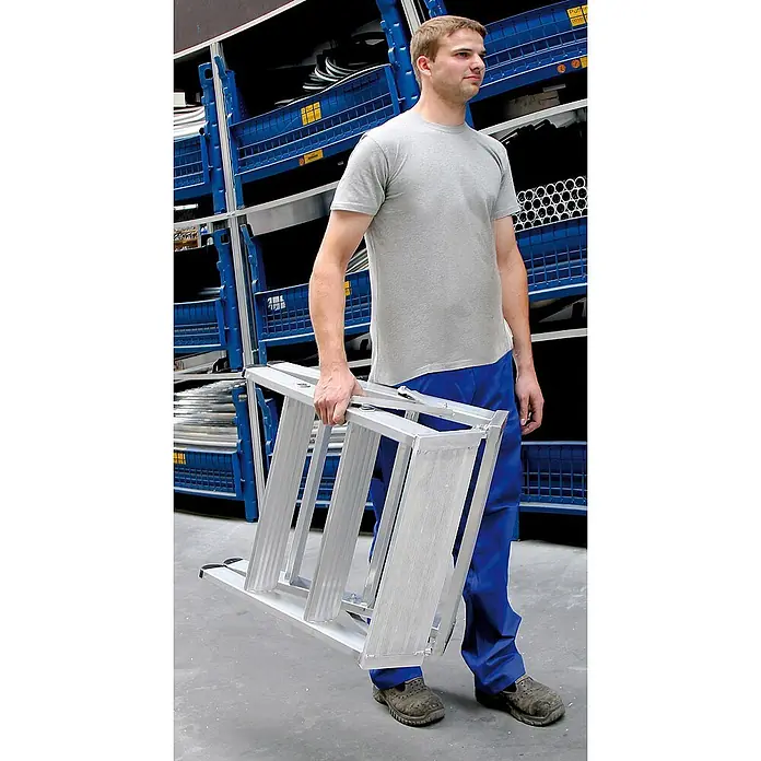 Munk Stehleiter Stufen Stehpodest klappbar, bedseitig begehbar 2x4 Stufen - Anzahl Tritte: 4 Stk., Arbeitshöhe: 2.930 m, Aluminium - Geklappte Aluminium-Trittleiter, von einem Mann getragen, zeigt ihr kompaktes, tragbares Design.