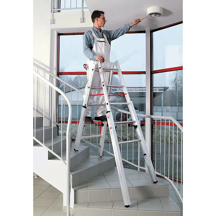 Euroline Stehleiter Premium 30576 Treppenstehleiter 2x8 Sprossen - Anzahl Tritte: 8 Stk., Arbeitshöhe: 3.600 m, Aluminium - Verstellbare silberne Aluminium-Klappleiter auf einer Treppe, für sicheren Zugang zu einer Deckenleuchte.