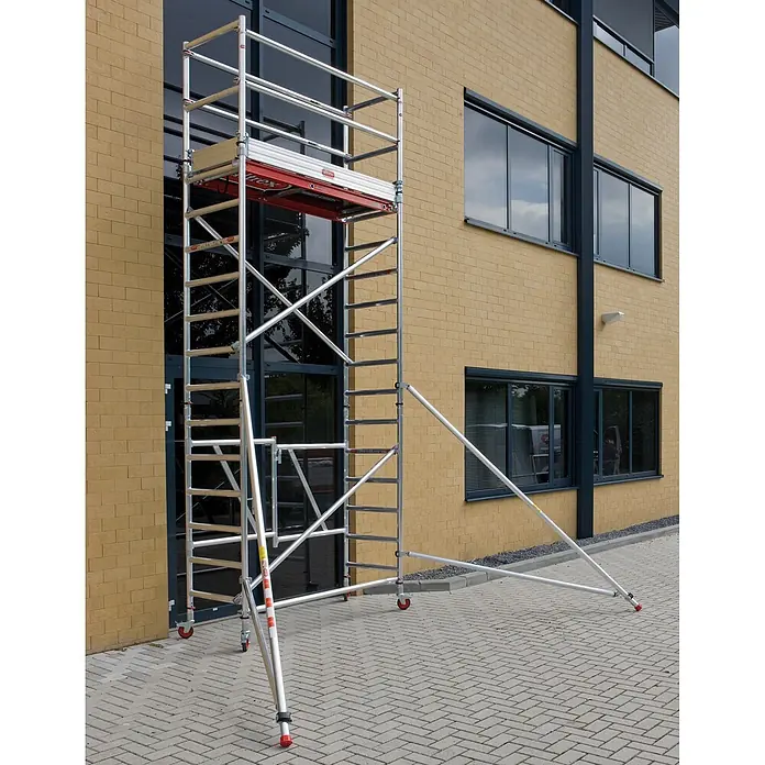 Altrex Rollgerüst Klappgerüst RS Tower 54 Alu Holz-Plattform 0,75x1,85m mit Safe-Quick 8,8m - Arbeitshöhe: 8.800 m - Mobiles Gerüst aus silbernem Aluminium mit roten Akzenten und Auslegern, neben einem Backsteingebäude.