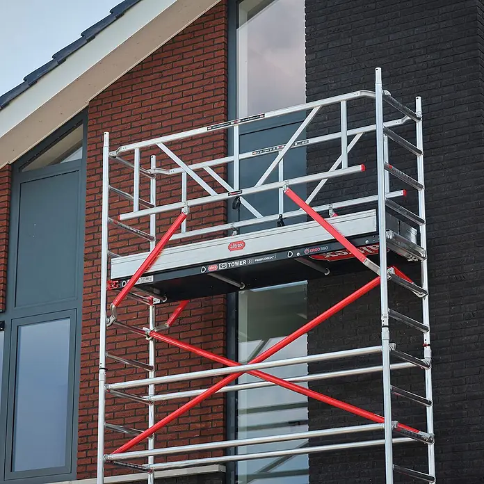 Altrex Rollgerüst Fahrgerüst RS Tower 51 Aluminium mit Fiber-Deck Plattform 5,20m AH schmal - Arbeitshöhe: 5.200 m - Mobiles Aluminiumgerüst mit roten Streben vor einem modernen Haus.