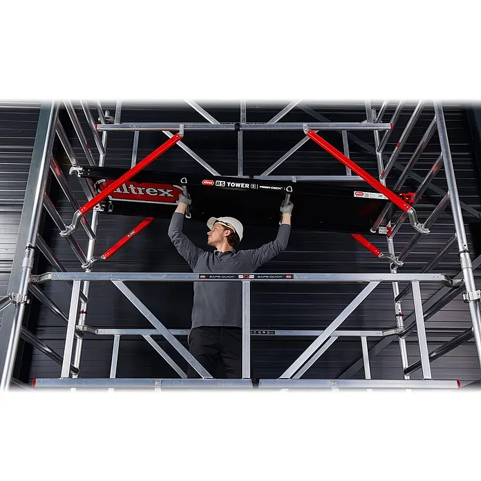 Altrex Rollgerüst Fahrgerüst RS Tower 52-S Aluminium mit Safe-Quick und Fiber-Deck Plattform - Arbeitshöhe: 12.200 m - Mann im Schutzhelm installiert schwarze Altrex RS TOWER 5 FIBER-DECK Plattform in silbernes Gerüst mit roten Streben.