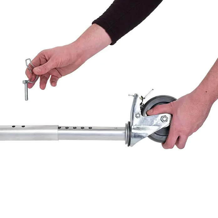Altrex Rollgerüst Klappgerüst RS Tower 34 Aluminium 0,75x1,65m schmal 7,80m Arbeitshöhe - Arbeitshöhe: 7.800 m - Hände befestigen eine graue Lenkrolle mit einem Metallstift an einer silbernen Metallstange.