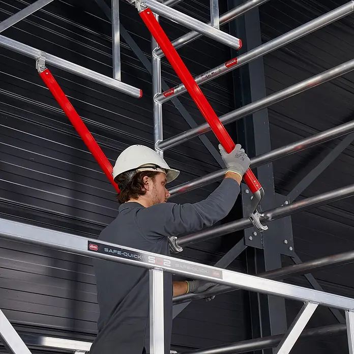 Altrex Rollgerüst Fahrgerüst RS Tower 52-S Aluminium mit Safe-Quick und Fiber-Deck Plattform - Arbeitshöhe: 12.200 m - Altrex Safe-Quick Aluminium-Gerüstsystem mit roten Sicherheitsstreben, von einem Arbeiter montiert.