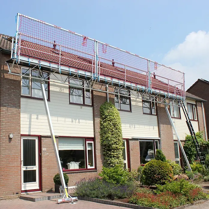 Altrex Rollgerüst Modulare Dreiecksbühne Absturzsicherung mit Fangnetzen für geneigte Däch -  - Dachsicherheitssystem mit Aluminiumrahmen und rotem Netz, an einem Haus für Dacharbeiten installiert.