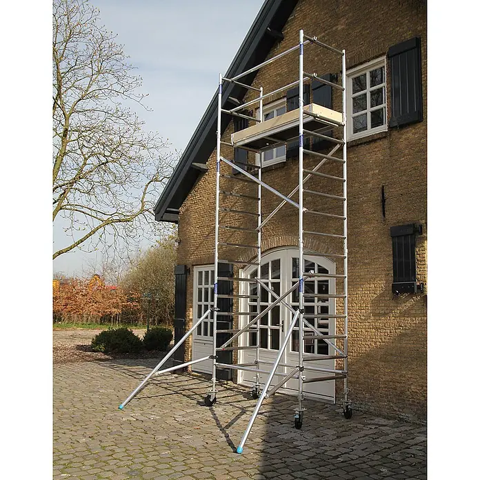 ASC Rollgerüst Rollgerüst Basic-Line 8,30m AH (DIN EN 1004:2004) - Arbeitshöhe: 8.300 m - Silbernes Aluminiumgerüst mit Rädern und Stützfüßen vor einem Ziegelhaus aufgestellt.