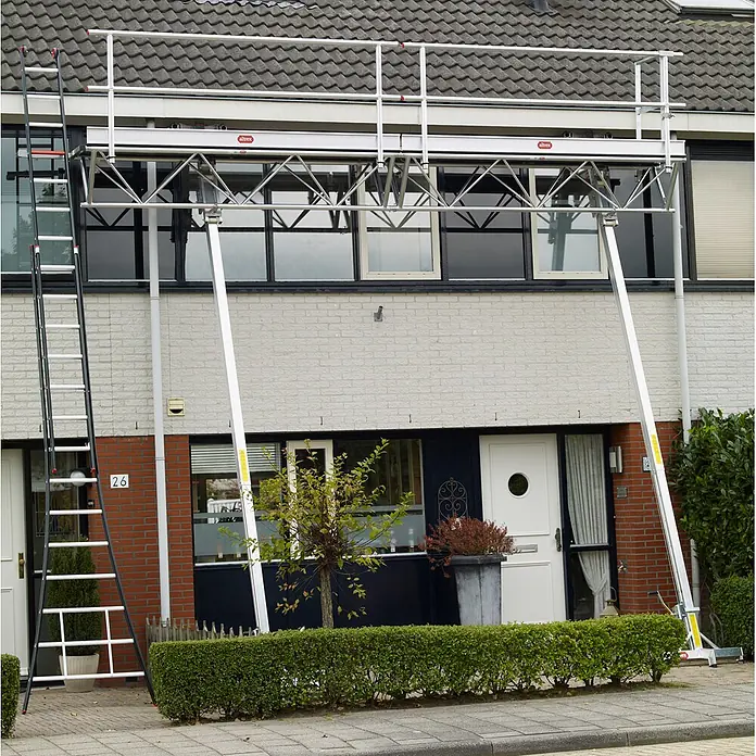 Altrex Rollgerüst Modulare Dreiecksbühne Euro 3-5 mit Handwinde MTB 6m lang -  - Silbernes Aluminium-Gerüst mit Leiter an einem zweistöckigen Haus für Außenarbeiten.