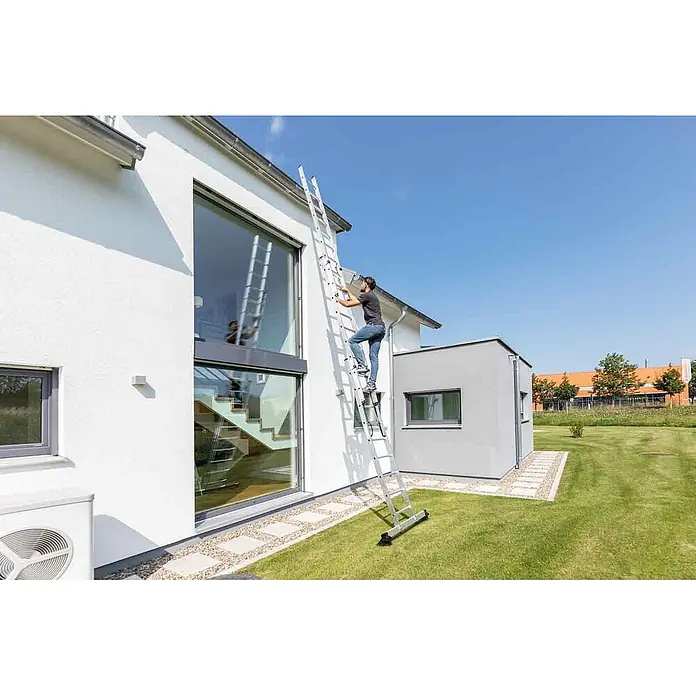 Munk Mehrzweckleiter Mehrzweckleiter mit Nivello® Traverse 3x8 Sprossen - Anzahl Tritte: 8 Stk., Arbeitshöhe: 6.900 m, Aluminium - Mann klettert auf ausziehbarer silberner Leiter, die an Hausfassade für Wartungsarbeiten lehnt.
