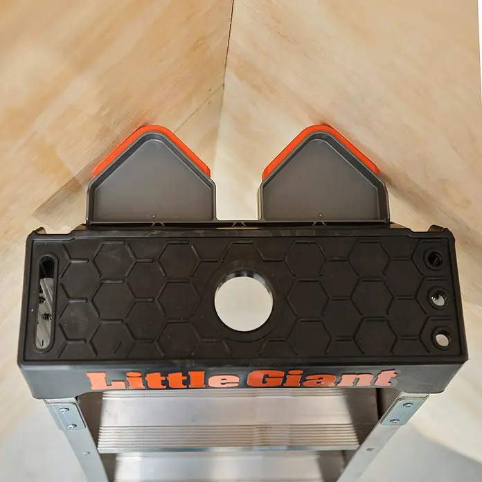 Altrex Mehrzweckleiter King Kombo 3-in-1 Stehleiter mit 6+3 Stufen - Anzahl Tritte: 9 Stk., Arbeitshöhe: 4.000 m - Schwarzes Little Giant Leiterzubehör mit orangefarbenen und grauen Polstern, das die Leiter in einer Ecke stabilisiert.