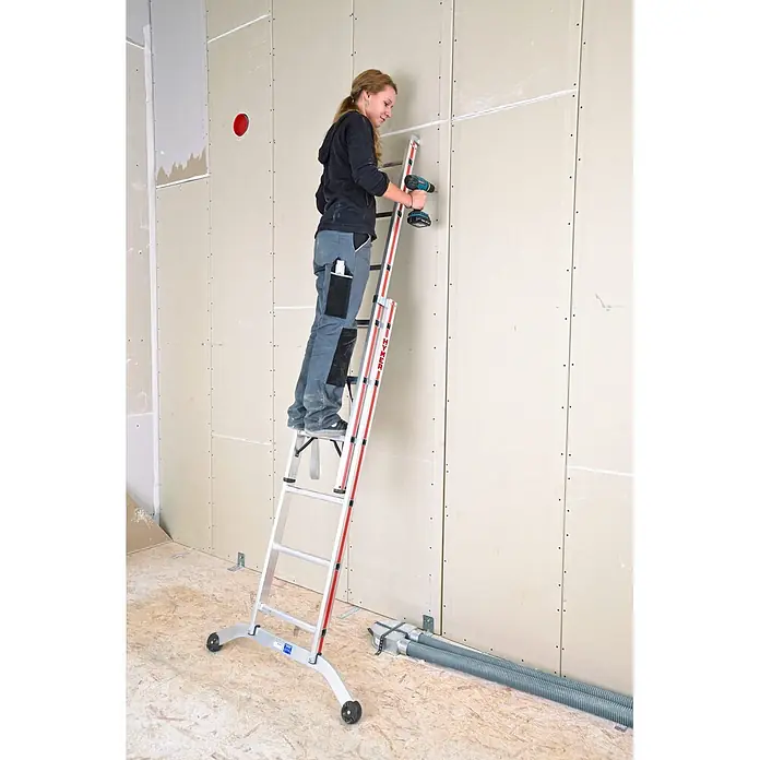 Hymer Mehrzweckleiter Mehrzweckleiter mit gebogener Traverse 2x14 Sprossen - Anzahl Tritte: 14 Stk., Arbeitshöhe: 7.980 m, Aluminium - Rollbare Aluminiumleiter in Silber und Rot, von einer Frau zum Arbeiten an einer Gipswand genutzt.