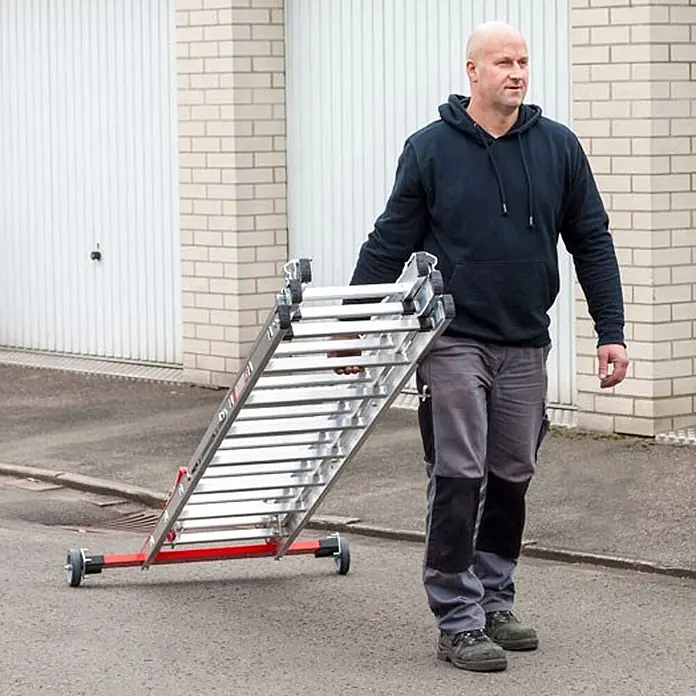 Euroline Mehrzweckleiter Premium 30778 Mehrzweckleiter 3-teilig 3x13 Sprossen - Anzahl Tritte: 13 Stk., Arbeitshöhe: 10.050 m, Aluminium - Silberne Aluminium-Mehrzweckleiter mit rotem und schwarzem Rollgestell wird von einem Mann transportiert.