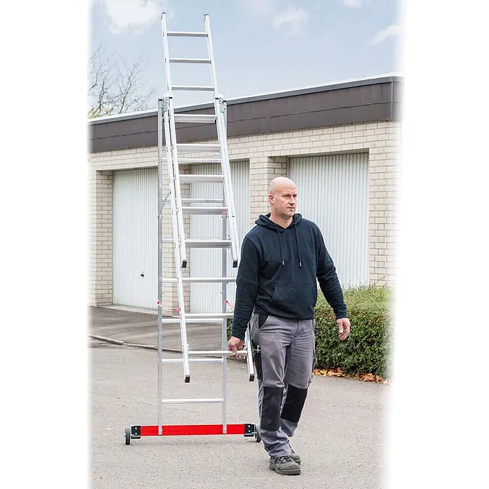 Euroline Mehrzweckleiter Premium 30778 Mehrzweckleiter 3-teilig 3x13 Sprossen - Anzahl Tritte: 13 Stk., Arbeitshöhe: 10.050 m, Aluminium - Ein Mann trägt eine silberne Aluminium-Mehrzweckleiter mit rotem Fuß. Die Leiter ist ausziehbar.
