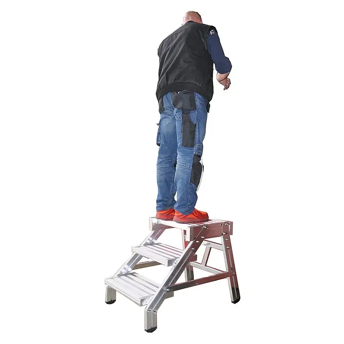 Euroline Arbeitsplattform 336 Arbeitstritt 3 Stufen - Anzahl Tritte: 3 Stk., Arbeitshöhe: 2.100 m, Aluminium - Aluminium-Klapptritt, auf dessen oberster Stufe eine Person in Jeans und Weste steht.