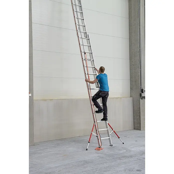 Hymer Seilzugleiter Seilzugleiter klappbarer Teleskopausleger 3x18 Sprossen - Arbeitshöhe: 12.840 m, Aluminium - Mann klettert in Industrieumgebung auf hohe Aluminium-Ausziehleiter mit roten Stabilisatorstützen.