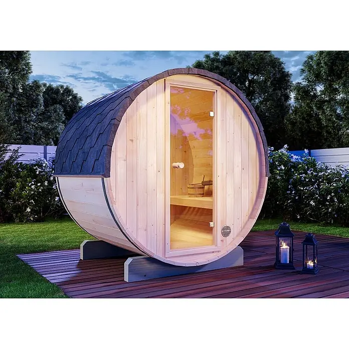 FinnTherm Fasssauna Mini XS - Holz - Fasssauna aus hellem Holz mit dunklem Dach und Glastür, auf einer Holzterrasse in der Abenddämmerung.
