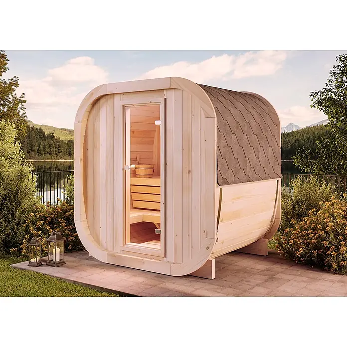 FinnTherm Fasssauna ScandiCube Mini XS - Holz, L x B x H: 166 x 21 x 214 cm - Helle Holzfasssauna mit dunklem Schindeldach und Glastür, im Freien an einem See gelegen.