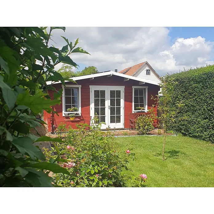 Fjordholz Gartenhaus Agnes 44 Farbbehandlung Lichtgrau - Außenmaß inkl. Dachüberstand (B x T): 500 x 400 cm, Holz, Naturbelassen - Ein charmantes, rotes Gartenhaus aus Holz mit weißen Doppeltüren und Fenstern, eingebettet in einen grünen Garten mit blühenden Rosen und hohen Hecken.