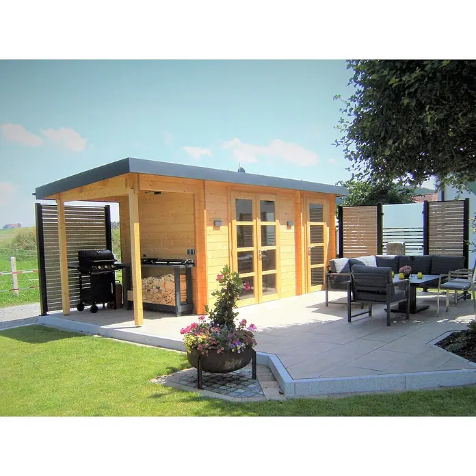 Fjordholz Gartenhaus Carin 44 A +SD - Außenmaß inkl. Dachüberstand (B x T): 606 x 220 cm, Holz, ohne Imprägnierung - Ein moderner Holzgartenpavillon mit dunklem Flachdach und gepflasterter Terrasse mit Gartenmöbeln und Grillplatz.