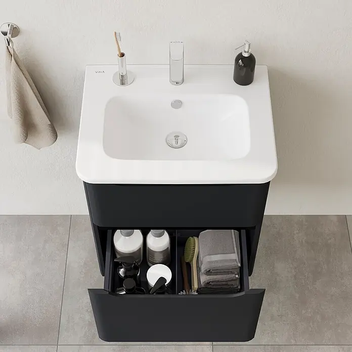 VitrA Integra Round Badmöbel-Set - Gesamtbreite Badmöbel: 60 cm, Graphit, Matt - Schwarzer Badunterschrank mit weißem Waschbecken und offener Schublade, die Pflegeprodukte zeigt.