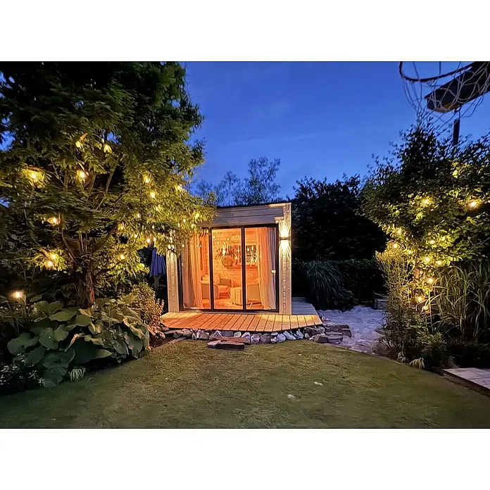 Fjordholz Gartenhaus Q-BIC Alu 70 G 6mm Einfachglas Grau Imprägnierung - Außenmaß inkl. Dachüberstand (B x T): 300 x 300 cm, Holz, Naturbelassen - Gemütliches Gartenhaus mit Glastüren, beleuchtetem Innenraum und Lichterketten bei Dämmerung.
