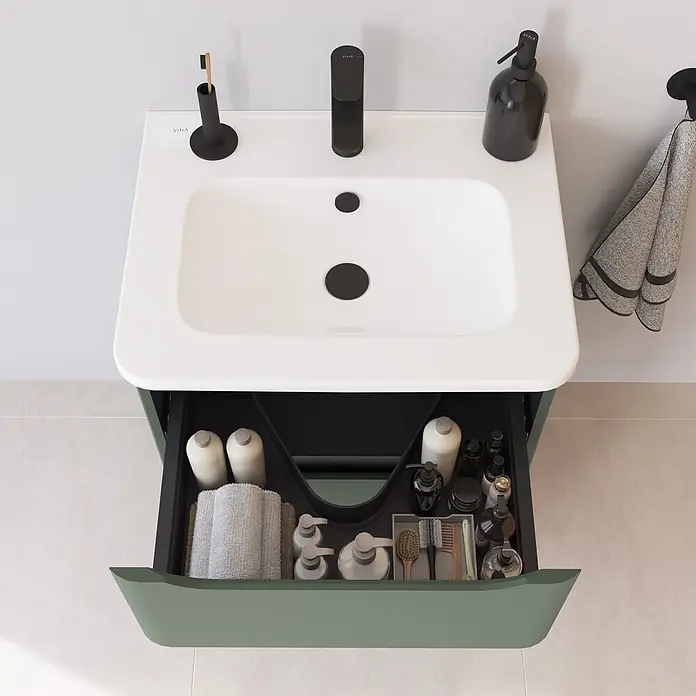 VitrA Integra Round Badmöbel-Set - Gesamtbreite Badmöbel: 60 cm, Moosgrün, Matt - Weißes Waschbecken mit schwarzem Wasserhahn und Accessoires, auf grünem Badmöbel mit offener Schublade und Kosmetikartikeln.
