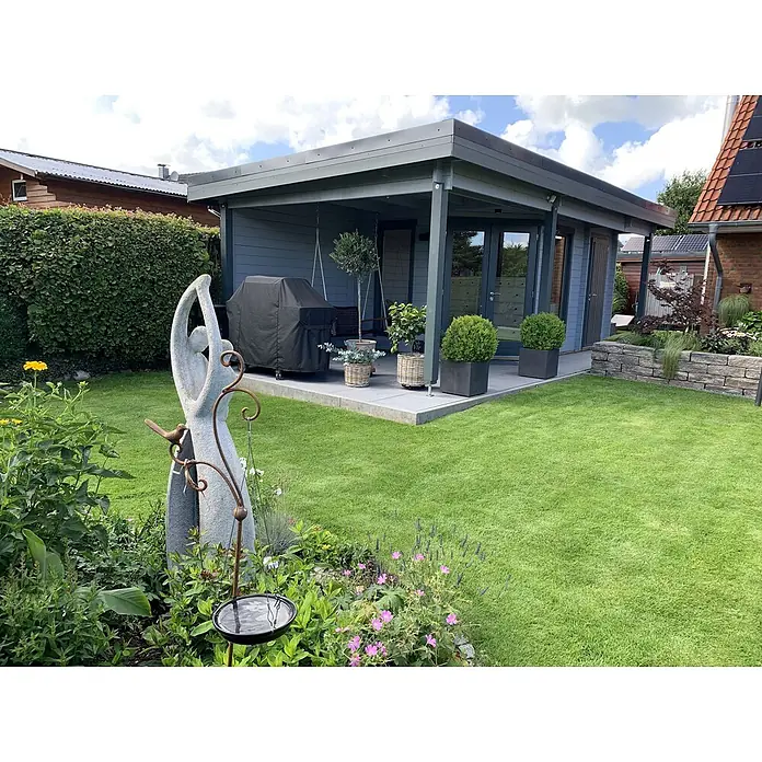 Fjordholz Gartenhaus Nora 44 H Modern - Außenmaß inkl. Dachüberstand (B x T): 740 x 320 cm, Holz, Farbbehandlung Lichtgrau - Graues Gartenhaus mit Terrasse in einem üppig grünen Garten. Es hat Glastüren und ist mit Topfpflanzen geschmückt.