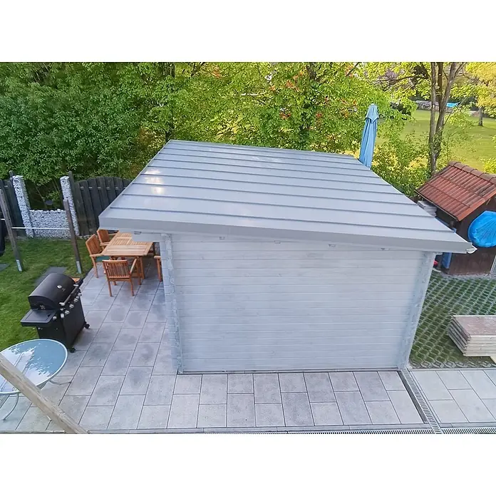 Fjordholz Gartenhaus Jacob 70 E - Außenmaß inkl. Dachüberstand (B x T): 480 x 360 cm, Holz, ohne Imprägnierung - Helles graues Gartenhaus aus Holz mit Metalldach auf einer gepflasterten Terrasse im Garten, von oben gesehen.
