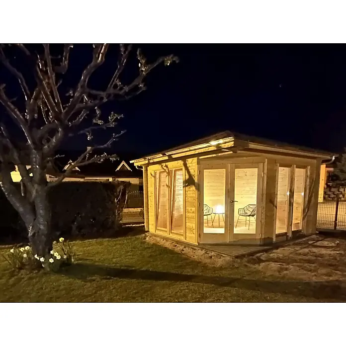 Fjordholz Gartenhaus Fargo 44 B - Außenmaß inkl. Dachüberstand (B x T): 380 x 380 cm, Holz, ohne Imprägnierung - Eine gemütliche Gartenhütte aus Holz mit beleuchtetem Innenraum, zwei Stühlen und einem Tisch, nachts im Garten.