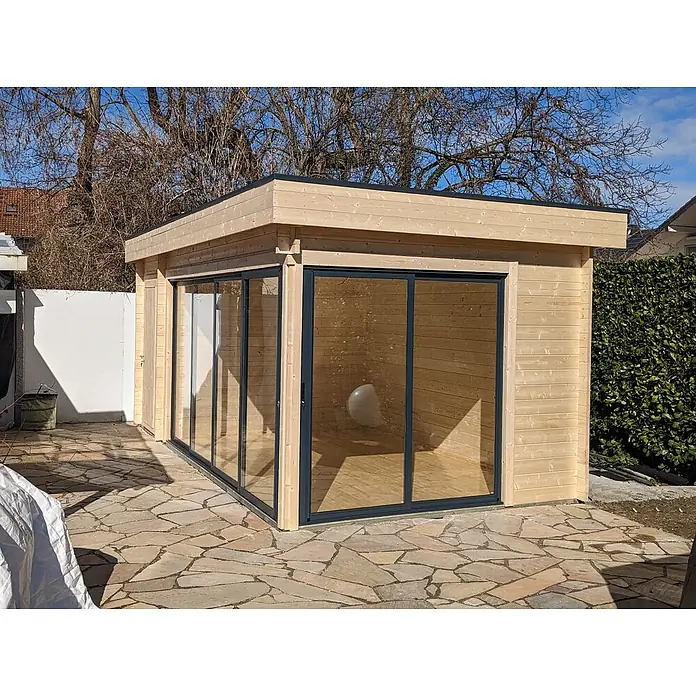 Fjordholz Gartenhaus - Außenmaß inkl. Dachüberstand (B x T): 595 x 320 cm, Holz, Grau Imprägnierung - Modernes Gartenhaus aus hellem Holz mit großen Glasschiebetüren und Flachdach auf Steinterrasse.