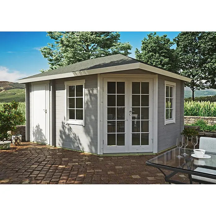 Fjordholz Gartenhaus Kiano 70 B - Außenmaß inkl. Dachüberstand (B x T): 470 x 320 cm, Holz, Grau Imprägnierung - Graues Gartenhaus aus Holz mit weißen Türen und Fenstern, auf einer Ziegelterrasse in einer Naturlandschaft.