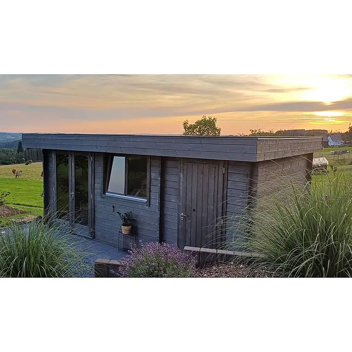 Fjordholz Gartenhaus Kurt 44 D Farblose Imprägnierung - Außenmaß inkl. Dachüberstand (B x T): 578 x 400 cm, Holz, Naturbelassen - Modernes, dunkelgraues Holzgartenhaus mit Flachdach und großen Fenstern, in ländlicher Umgebung mit grünen Feldern und Abendhimmel.
