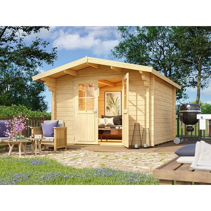 Fjordholz Gartenhaus Berlin 70 A Classic - Außenmaß inkl. Dachüberstand (B x T): 320 x 380 cm, Holz, ohne Imprägnierung - Eine helle Holzhütte mit offener Tür, die einen Innenraum zeigt, und einem Sitzbereich im Freien, eingebettet in einen sonnigen Garten.