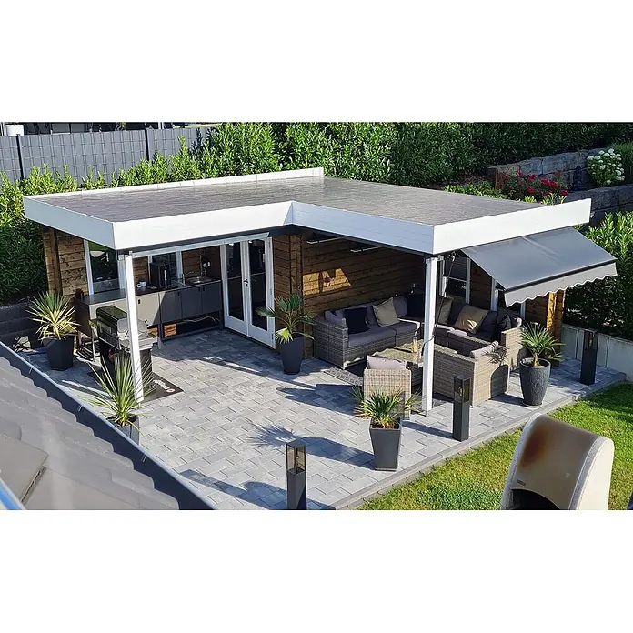 Fjordholz Gartenhaus Fred 44 Grau Imprägnierung - Außenmaß inkl. Dachüberstand (B x T): 573,2 x 573,2 cm, Holz, Naturbelassen - Moderne L-förmige Terrassenüberdachung mit weißem Rahmen, die eine hölzerne Außenküche und einen Loungebereich auf grauen Pflastersteinen beherbergt.