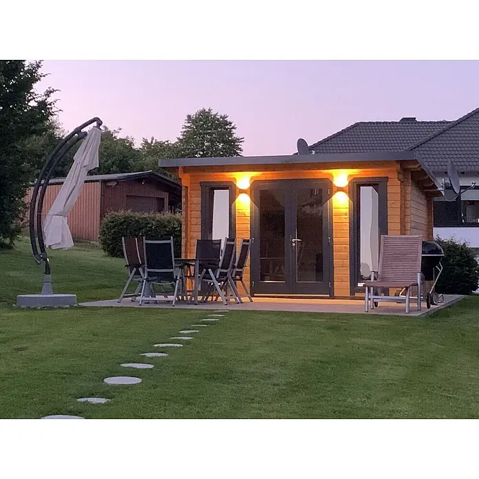 Fjordholz Gartenhaus Jacob 70 C - Außenmaß inkl. Dachüberstand (B x T): 420 x 360 cm, Holz, Farblose Imprägnierung - Gemütliches Gartenhaus aus Holz mit Beleuchtung, Terrasse mit Möbeln und Trittsteinen auf grünem Rasen.