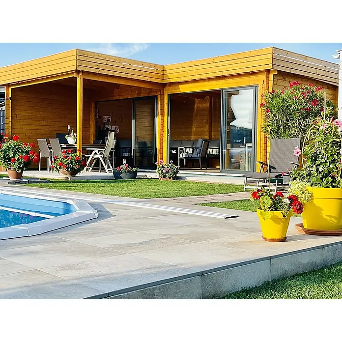 Fjordholz Gartenhaus - Außenmaß inkl. Dachüberstand (B x T): 710 x 598 cm, Holz, Naturbelassen - L-förmiges Holzgartenhaus mit Glasschiebetüren, umgeben von Terrasse, Pool und Grünflächen.