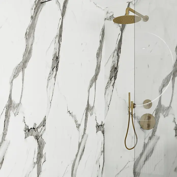 Wetwall Wandpaneel Elite - 16 x 242 cm, Calacatta Statuario, Abgerundete Kante - Goldener Duschkopf, Handbrause und Armaturen an einer weißen Marmorwand hinter einer Glaswand.
