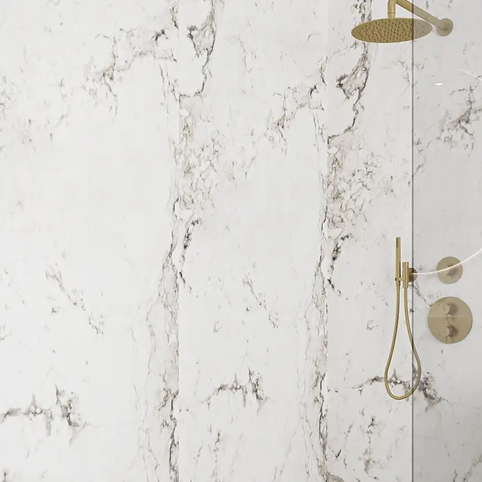 Wetwall Wandpaneel Elite - 16 x 242 cm, Romana Marble, Abgerundete Kante - Goldene Duscharmaturen mit Regenduschkopf, Handbrause und Bedienknöpfen, an einer weißen Marmorwand in einer Dusche montiert.