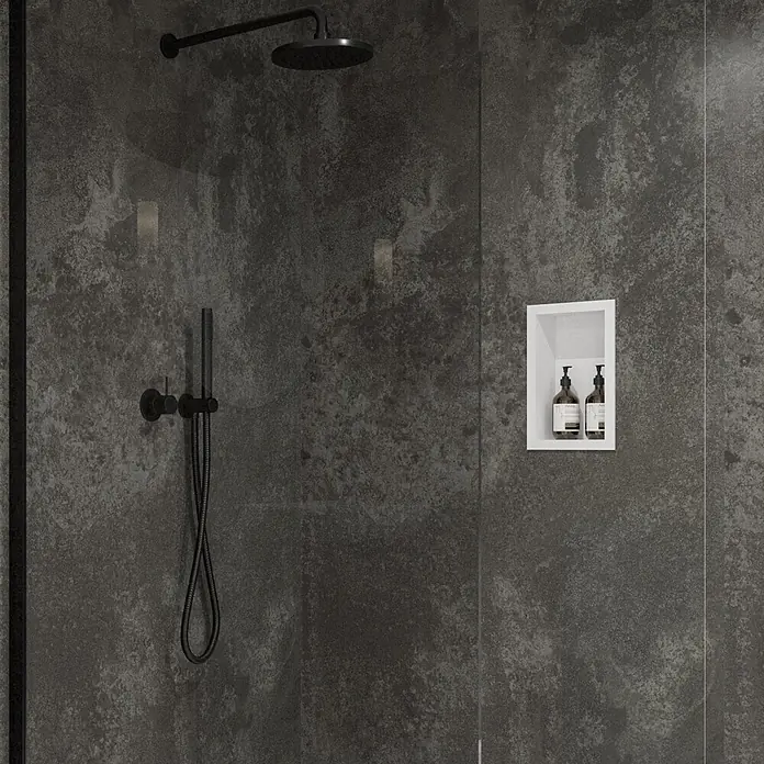 Wetwall Wandpaneel Elite - 16 x 242 cm, Magma, Abgerundete Kante - Modernes Duschsystem in Mattschwarz: Regenduschkopf und Handbrause. Eine weiße Nische mit zwei Flaschen ist auf einer dunklen texturierten Wand.